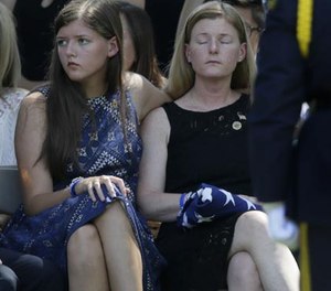 Heidi Smith, right, holds a flag with her daughter Victoria Smith during graveside services for her husband Dallas police Sgt. Michael J. Smith at Restland Funeral Home and Cemetery in Dallas, Thursday, July 14, 2016.