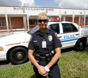 In this Thursday, Aug. 22, 2013 photo, Dara Van Antwerp, the school resource officer at Panther Run Elementary School is shown beside her patrol car at the school in Pembroke Pines, Fla.