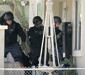 Phoenix SWAT team members prepare to move in on a house during a police standoff with an armed man in Phoenix on Friday, July 7, 2006. The man was wanted on a probation violation warrant. (AP Photo/Khampha Bouaphanh)