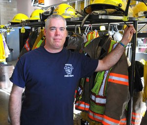 In this Nov. 4, 2016 photo, Scott Geiselhart stands next to turnout gear at the Frazee Fire Department fire hall in Frazee, Minn.