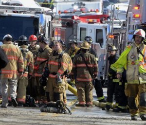 Firefighters stand by the scene of a fire after a wall collapsed in York, Pa.