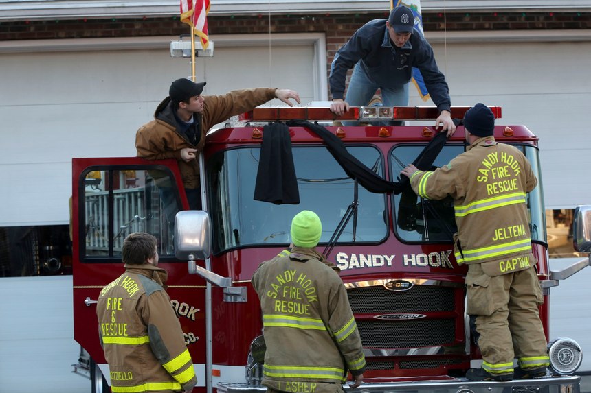 Sandy Hook firefighters hang bunting on their fire truck, Saturday, Dec. 15, 2012, in Sandy Hook village of Newtown, Conn.