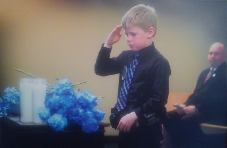 Thomas Mechels salutes his fallen father during a South Dakota Police Memorial Service.