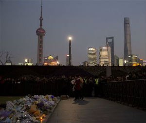 A woman prepares to lay flowers at the site of a deadly stampede in Shanghai, China, Thursday, Jan. 1, 2015. People unable to contact friends and relatives streamed into hospitals Thursday, anxious for information after a stampede during New Year's celebrations in Shanghai's historic waterfront area killed dozens of people in the worst disaster to hit one of China's showcase cities in recent years. (AP Photo/Ng Han Guan)