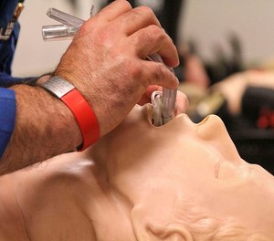 A paramedic demonstrates how to intubate a patient during training.