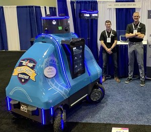 Robotic Assistance Devices staff members pose with ROAMEO, a security and concierge robot, at the 2021 IAAPA Expo in Orlando, Florida.