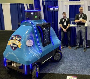 Robotic Assistance Devices staff members pose with ROAMEO, a security and concierge robot, at the 2021 IAAPA Expo in Orlando, Florida.