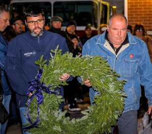 Two members of Firefighter Jon Davies' crew, Rescue 1 Group 4, carry a wreath to place next to the memorial at the Franklin Street fire station on Sunday, the eighth anniversary of Davies' death in the line of duty.