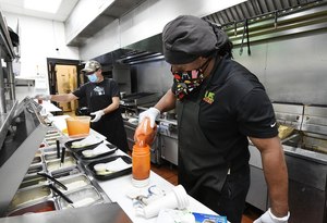 Ronald Showers (right) and Carlos Botello (left) in the kitchen of Billy's Sports Grill in Birmingham using masks and gloves. Image: al.com/Joe Songer via TNS