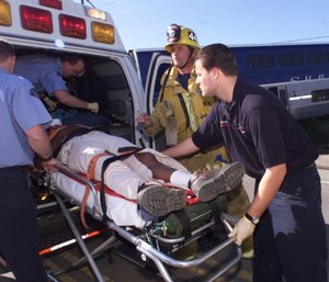 An American Medical Response paramedic, right, and a Ventura County firefighter help an injured man. (Bryan Chan/Los Angeles Times/TNS)