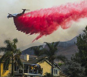 An air tanker makes a fire retardant drop behind homes in California.