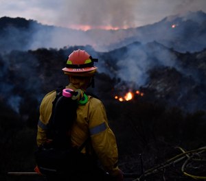 A firefighter watches flames from the Palisades Fire at Topanga State Park on May 15, 2021. An arson suspect has been arrested in the blaze that forced 1,000 people to evacuate and injured one firefighter.