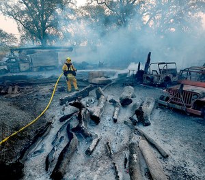 A firefighter mops up hot spots from the Kincade fire after it jumped Chalk Hill Road near Healdsburg, Calif. on Sunday morning, Oct. 27, 2019. (Luis Sinco/Los Angeles Times/TNS)