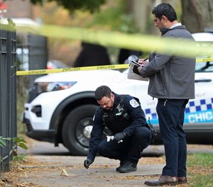 A Chicago police officer collects blood samples at a fatal shooting scene in the 900 block of East 54th Place in the Hyde Park neighborhood on Nov. 9, 2021, in Chicago