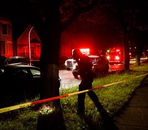 An officer examines the ground while a person who was shot sits in the ambulance before being transported on the 5500 block of South Carpenter Street Thursday July 5, 2018 in Chicago. (Armando L. Sanchez/Chicago Tribune/TNS)