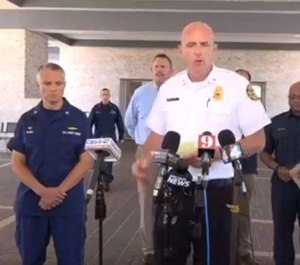 Interim Jacksonville Fire Chief Keith Powers speaks about the cessation of the search for two missing firefighters Thursday, joined by Coast Guard Capt. Mark Vlaun (left) and other fire officials. (Photo/Tribune News Service, First Coast News)