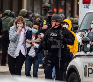Health care workers walk out of a King Soopers grocery store after a gunman opened fire on March 22, 2021, in Boulder, Colorado.