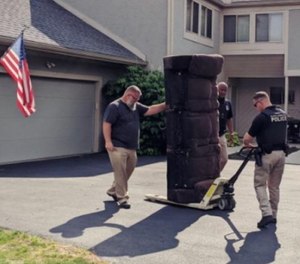 Officer Anthony Roberts (center), his Mobile Crisis Response Unit partner Phil McGeorge and Sgt. Matt Harris (right) move furniture into Dominique's apartment. (Photo/Starfish Assignment Columbus via TNS)