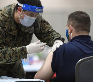A member of the U.S. Armed Forces administers a COVID-19 vaccine to a police officer on March 2, 2021, in Philadelphia, Pennsylvania.
