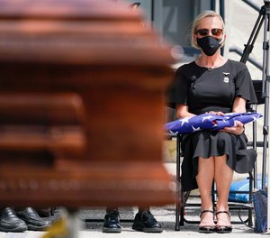 Karen Weiskopf, the widow of St. Petersburg, Florida, police Officer Michael Weiskopf, holds the ceremonial flag in her lap during her husband’s funeral at The Coliseum, on Tuesday, Aug. 31, 2021, in St. Petersburg. Weiskopf was unvaccinated and died from complications from COVID-19.