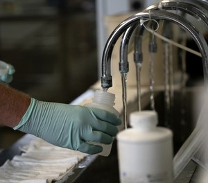 A geologist with the Illinois Environmental Protection Agency collects samples of treated Lake Michigan water in a laboratory at the water treatment plant in Wilmette, Illinois, on July 3, 2021.