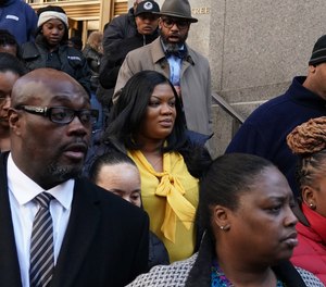 In this photo from November 25, 2019, Metropolitan Correctional Center guard Tova Noel (yellow shirt) surrounded by supporters leaves Federal Court in New York City.