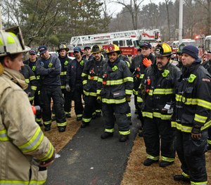 Under new protocol, firefighters listen to comments by a chief after they fought a 2-alarm fire at 63 Overlook Drive in Worcester. The on-scene discussions seek to give firefighters a more immediate look at their efforts after a fire.