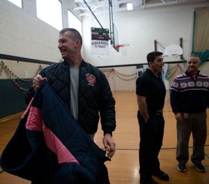 Rich Lutton along with other Jackson firefighters help students try on new coats at Frost Elementary School Friday Dec. 10, 2019. Members of the Jackson Fire Department gave out a total of 110 coats at Frost Elementary School. (Photo/Nicole Hhester, MLive.com)