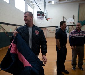 Rich Lutton along with other Jackson firefighters help students try on new coats at Frost Elementary School Friday Dec. 10, 2019. Members of the Jackson Fire Department gave out a total of 110 coats at Frost Elementary School.