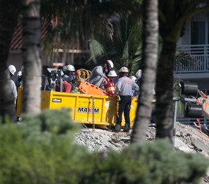 Search and rescue workers load gear and tools into a bin while working on the collapsed Champlain Towers south site.