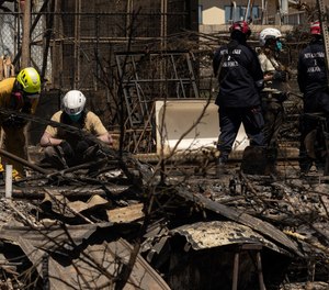 Search and recovery team members check charred buildings and cars in the aftermath of the Maui wildfires in Lahaina, Hawaii