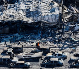 A man walks along Lahaina's Front Street on Aug. 11, 2023, past the burned carcasses of cars that couldn't escape a catastrophic wildfire that swept through the Maui, Hawaii.