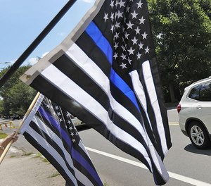 A car passes supporters of law enforcement holding “thin blue line