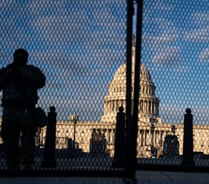 National Guard troops stand behind security fencing with the dome of the U.S. Capitol Building behind them on Saturday, Jan. 16, 2021, in Washington, D.C.