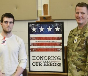 Jason Ricci, left, and Jeremy Degeier with a painting honoring Chief Warrant Officer 2 James A. Rogers Jr., who died in a helicopter crash in December. (Photo/Zachary Dwyer of St. Cloud Times via TNS)