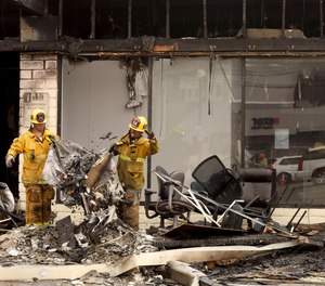 Firefighters clean up after an early morning fire that broke out in a strip mall where fire officials say 17 cats perished when fire raced through a feline overnight boarding facility and several other businesses in Culver City, Calif., on Saturday.
