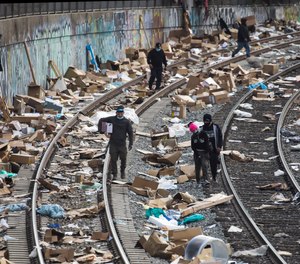People rummage through stuff stolen from cargo containers littered on Union Pacific train tracks in the vicinity of Mission Boulevard on Jan. 15, 2022, in Los Angeles.