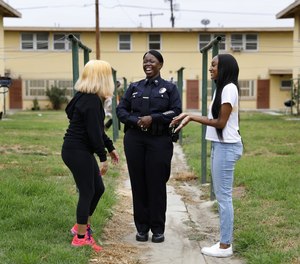 Newly appointed LAPD Deputy Chief Emada Tingirides, center, chats with two teenagers at Nickerson Gardens in Watts on Thursday, July 23, 2020.