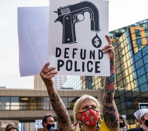 A protestor holds a sign reading 'Defund the Police,' outside Hennepin County Government Plaza during a demonstration on Aug. 24, 2020, in Minneapolis.