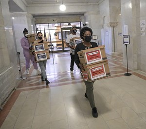 Corenia Smith, campaign manager with Yes 4 Minneapolis, carries boxes of signed petitions calling for replacing the Minneapolis Police Department with a new public safety department.