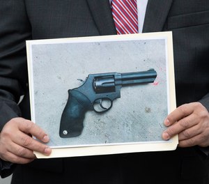 A detective holds a photo of a gun recovered from a police involved shooting on East 163rd Street at Fox Street on Tuesday, Nov. 2, 2021 in the Bronx, New York.