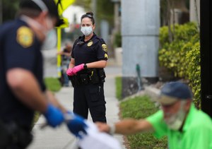 Clearwater Police officer Joseph Czop, on left, and Sgt. Meg Hasty, in center, both wearing protective face masks and gloves. Law enforcement officers are facing a new array of challenges policing during a global pandemic. Image: Dirk Shadd/Times via TNS