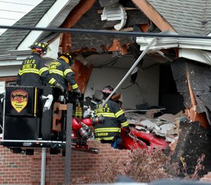 Firefighters inspect a car that crashed into the second story of a building in New Jersey Sunday morning. (Photo/Ed Murray, NJ Advance Media)