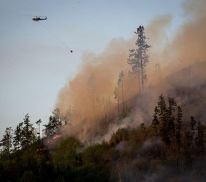 A helicopter heads back to a water source to get more water to dump on the Dowens Road 2 Fire near the Dorena Grange near Cottage Grove. (Photo/Andy Nelson, The Register-Guard, Tribune News Service)