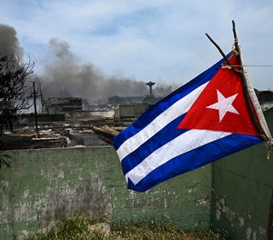 A Cuban flag flutters near a destroyed area of the fuel depot that was engulfed in flames for five days after lightning struck one of its tanks in Matanzas, Cuba, on Aug. 10, 2022.