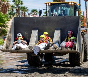Residents from Affinity Senior Living facility are held by firefighters in a frontloader while being brought to safety after floodwaters from Tropical Storm Hilary inundated Cathedral City.
