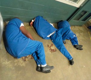 A handout photo shows three inmates sleeping on the floor with no bedding at the clinic of the Los Angeles County jail system's Inmate Reception Center.