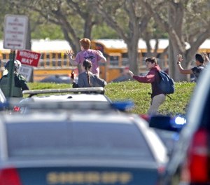 Students run wth their hands in the air outside of Stoneman Douglas High School in Parkland, Fla. after reports of an active shooter on Wednesday, Feb. 14, 2018. (John McCall/Sun Sentinel/TNS)
