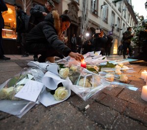 A woman lights a candle near the Strasbourg Christmas market.