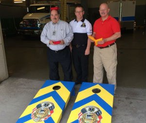 T. Steve Gardner (on the right) with the handmade, custom built Wake County EMS cornhole set.